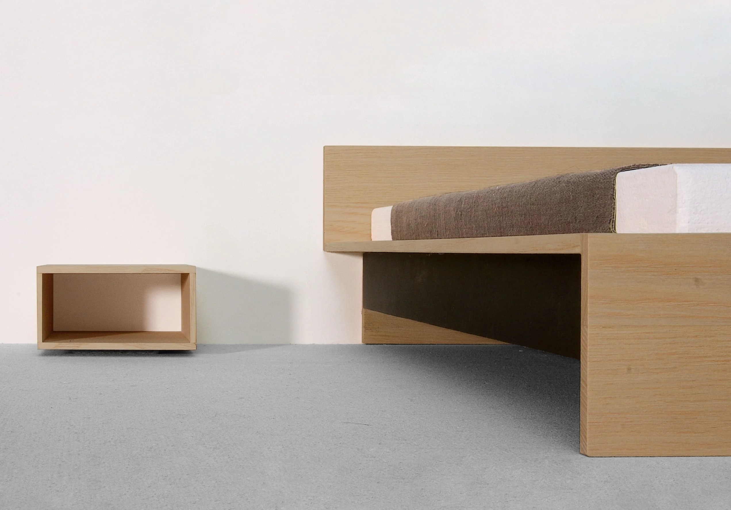 Bett aus Holz mit breitem Kopfteil und offenem Nachttischkubus.