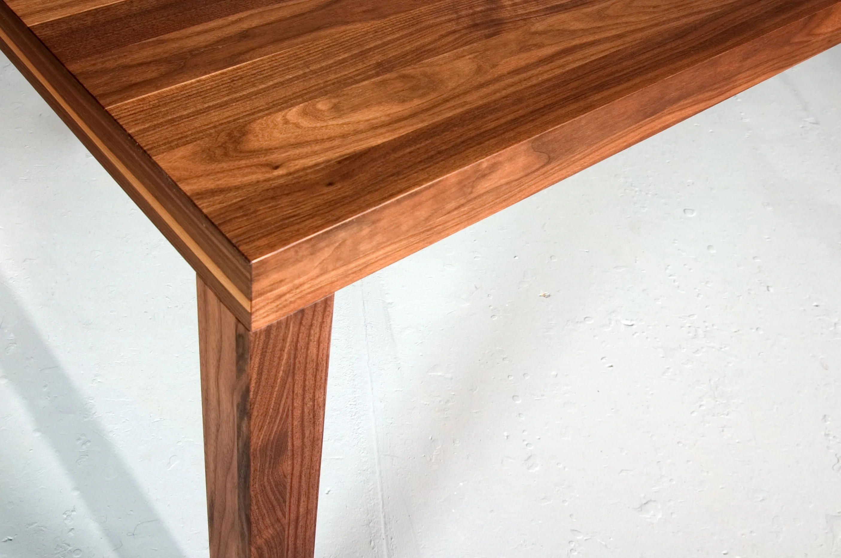 Nahaufnahme einer Tischecke aus dunklem Holz mit schlankem Bein.