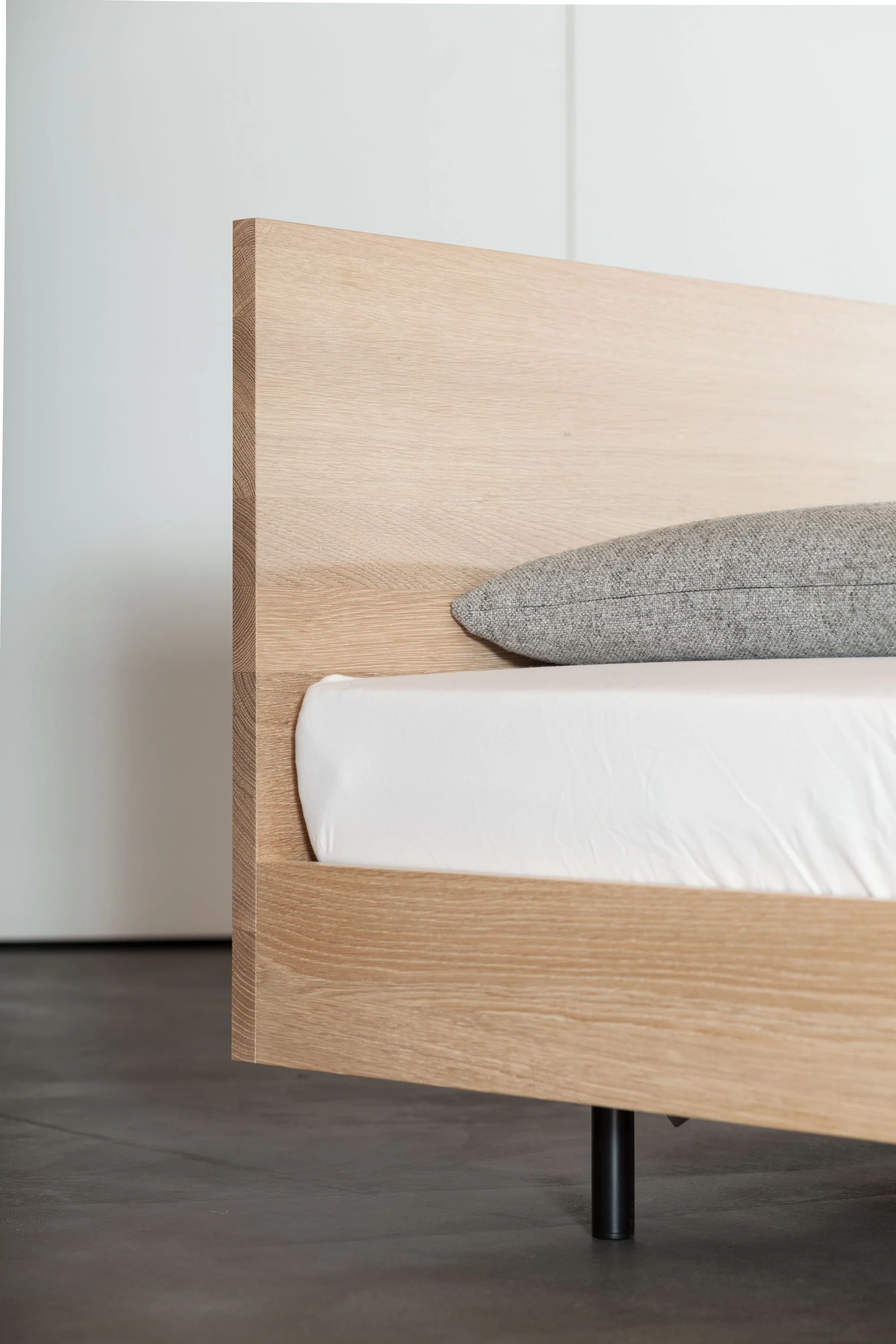 Kopfteil eines Bettes aus hellem Holz mit Kissen.